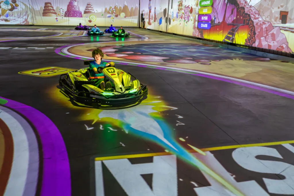 Karts competing on a colourfully projected track